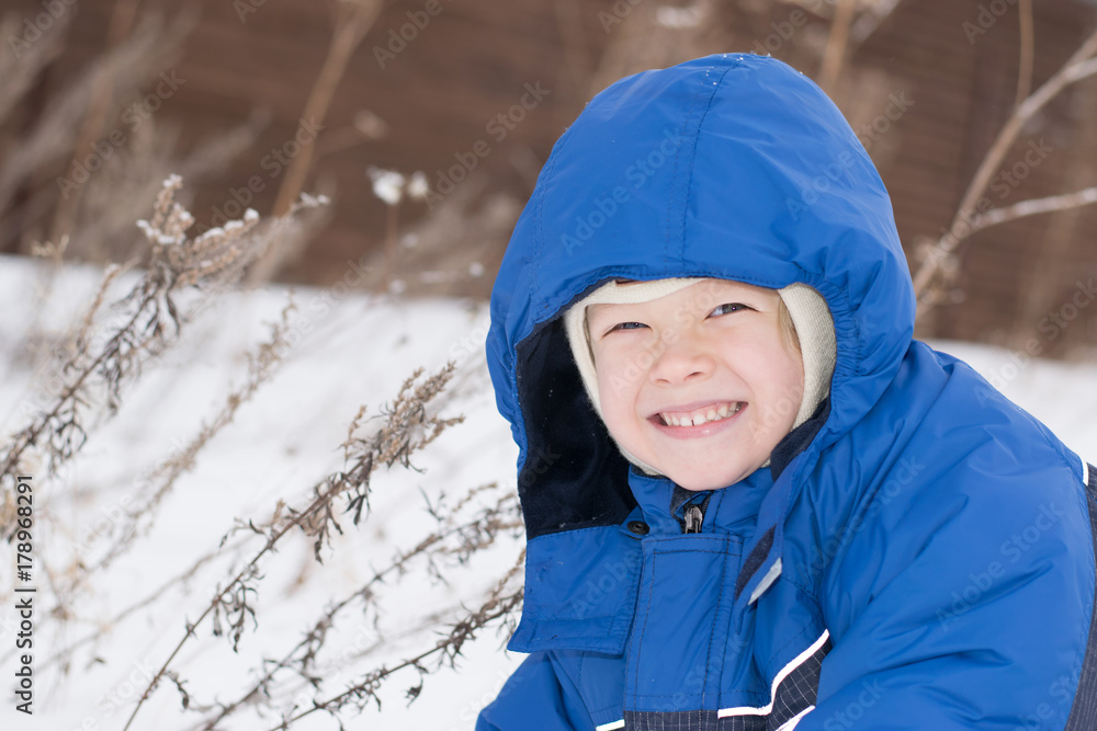 Happy boy lying in a snow - winter leisure for children