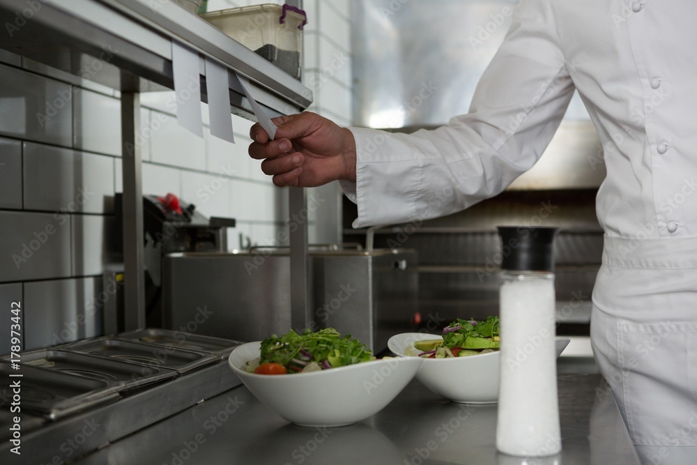 Fototapeta premium Male chef reading order in the kitchen