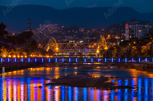 Night view of illuminated Malyy Kubanskiy bridge, Sochinskiy bridge Sochi river with lights reflected in its water, Sochi, Russia
 photo