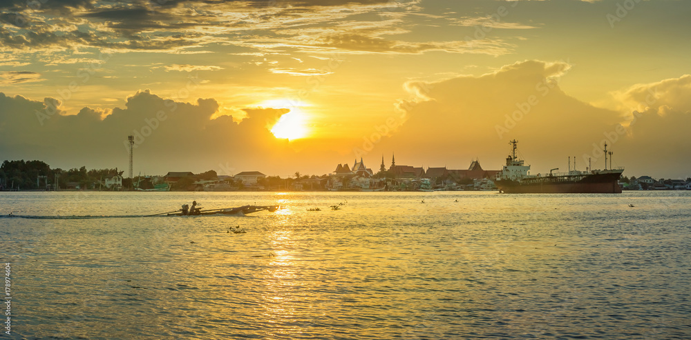 Panorama of the mouth of the Tha Chin River in the evening with cargo boats and fishing boats parked.