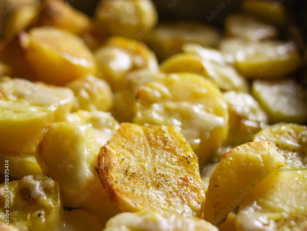 Raw potatoes prepared for baking with flavorings and cheese on tray. Raw potatoes prepared for baking with flavorings and cheese on tray.