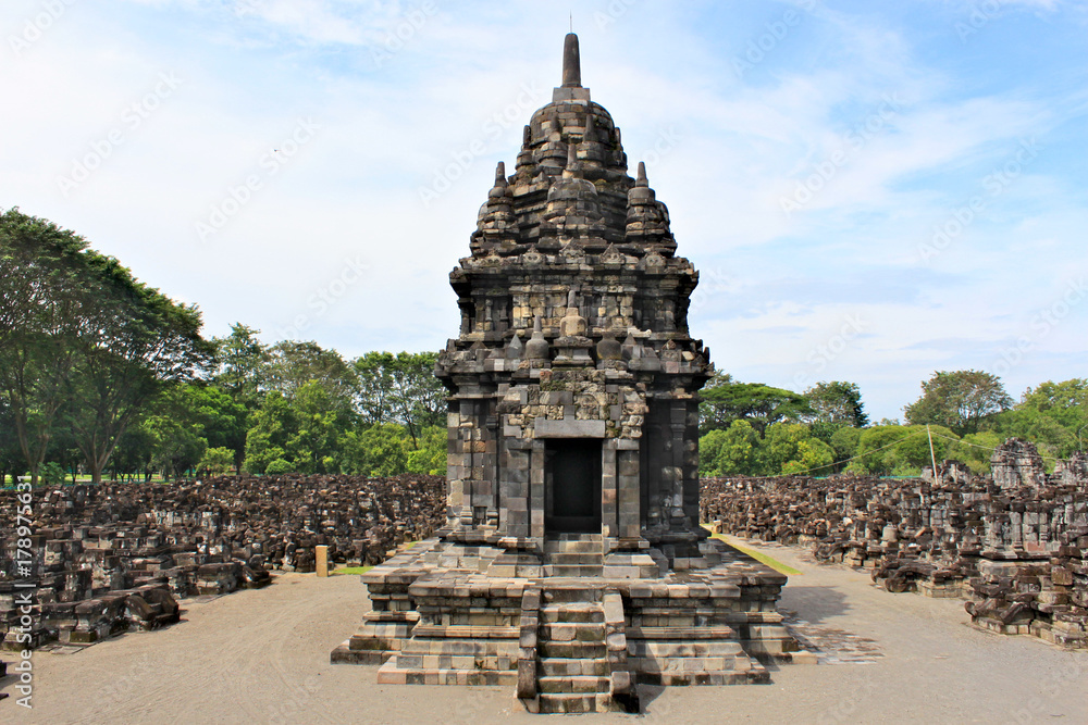 Obraz premium Sewu Temple is the second largest Buddhist temple complex in Java; built in 8th century; blue sky with white clouds and green trees around the ruins