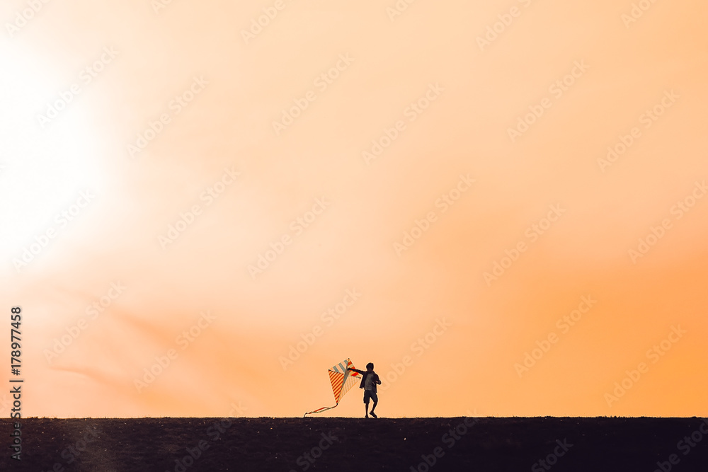  boy launching a kite. silhouette of a child with a kite in hands on a sunset background. Happy time of childhood. the wind of change. The concept of future. Copy space for your text