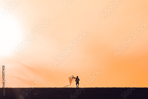  boy launching a kite. silhouette of a child with a kite in hands on a sunset background. Happy time of childhood. the wind of change. The concept of future. Copy space for your text