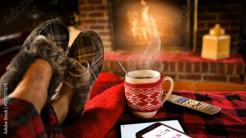 Cinemagraph of steaming hot coffee by fire in living room at Christmas feet rest on sofa