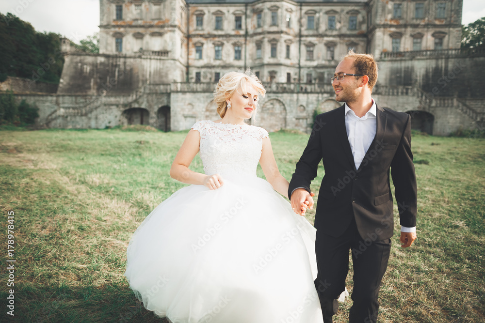Beautiful fairytale newlywed couple hugging near old medieval castle
