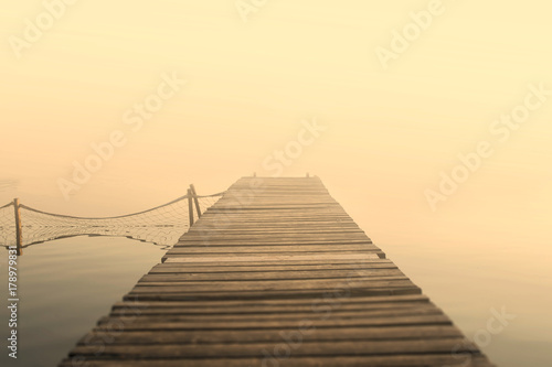 Wooden pier in the mist. Yellow and orange background. Nature background. Serenity and peace