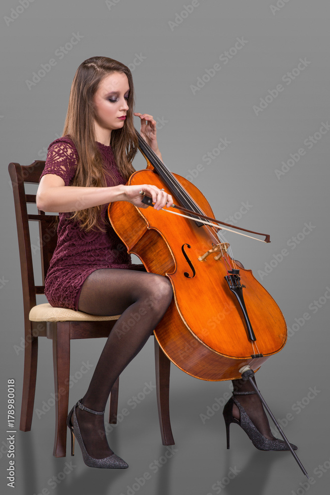 Beautiful young woman playing cello. Isolated on grey background Beautiful young woman playing cello. Isolated on grey background