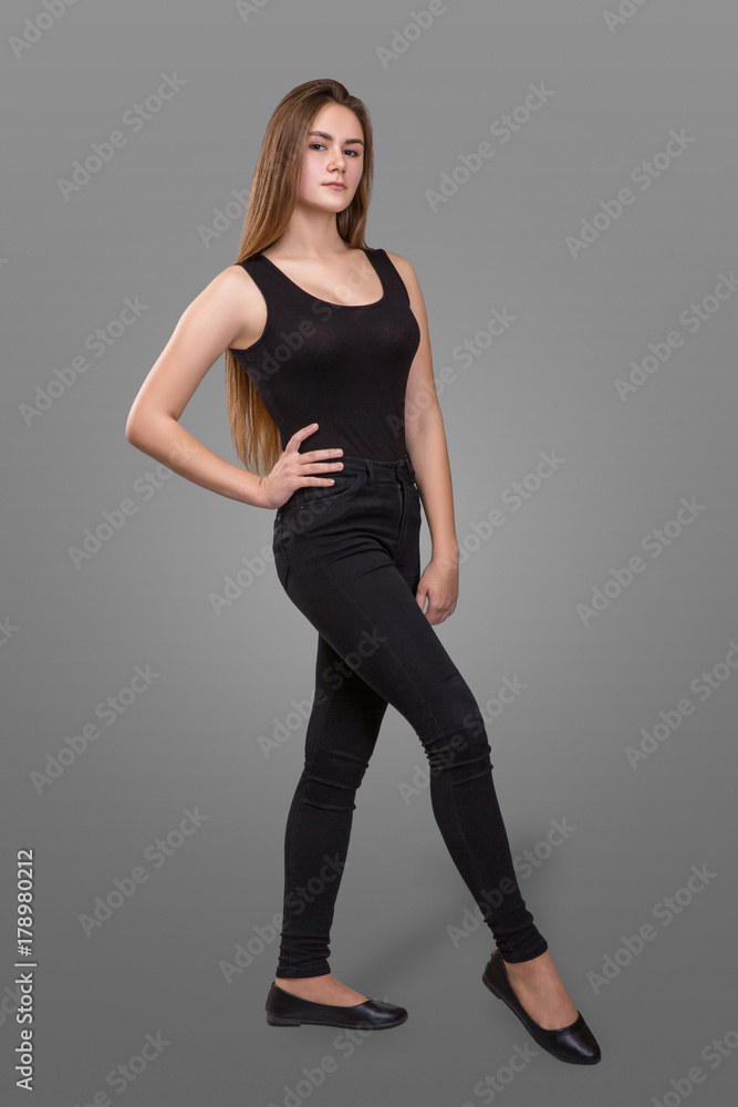 Fashion portrait of a beautiful girl in blank black shirt and black pants on a gray background. Studio shot. Model test. Fashion portrait of a beautiful girl in blank black shirt and black pants on a gray background. Studio shot. Model test.