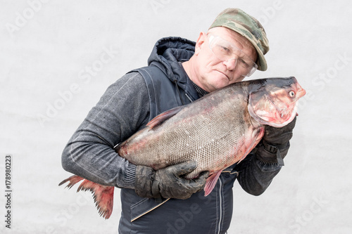 An elderly fisherman shows a large fish.