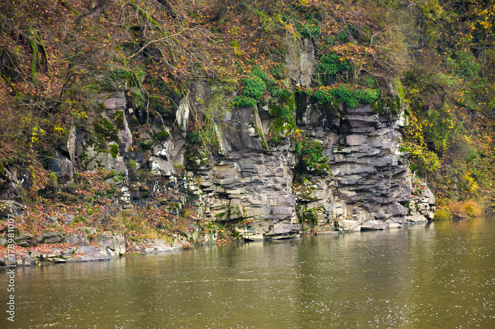 rocky cliff over the river in forest. beautiful autumn background with lots of textures