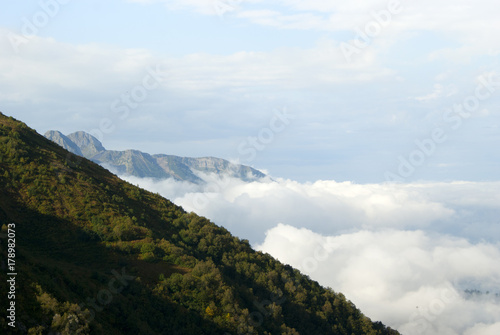 a view from above on cumulus clouds to the horizon  from which mountain ridges rise..