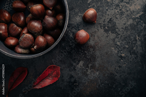 Chestnuts on dark black rustic background. Top view, copy space.