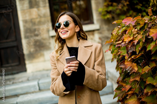 Young woman with mobile phone at autumn outdoor
