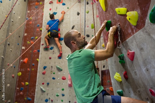 Fit athletes climbing wall in club