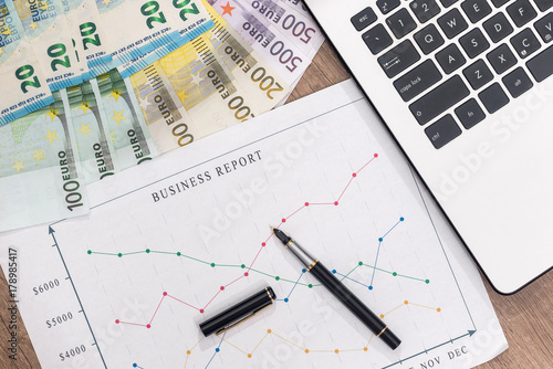 business graph with pen and laptop, euro banknote on desk