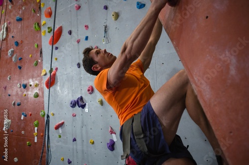 Confident male athlete rock climbing in health club