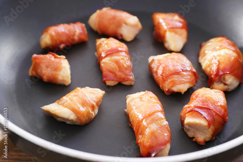 Bacon wrapped chicken in frying pan, closeup