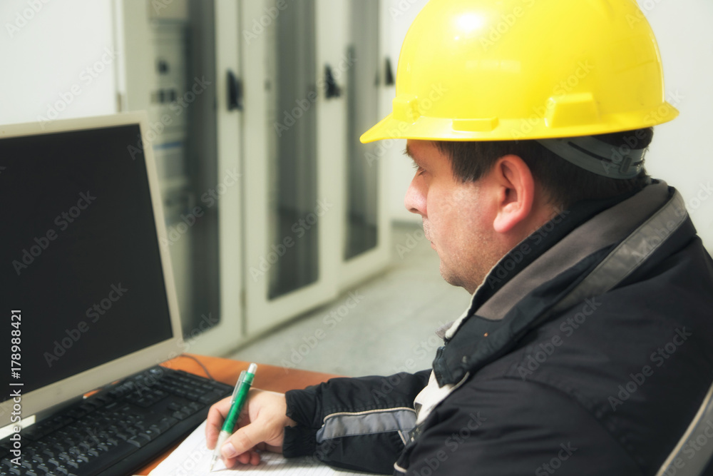 Technician take notes in the power plant control center Technician take notes in the power plant control center