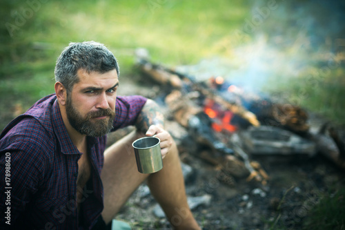 Man traveler with mug relax at bonfire on nature