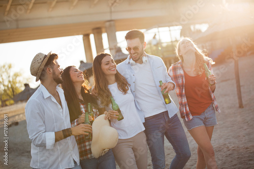 Group of young cheerful friends walking and drinking beer
