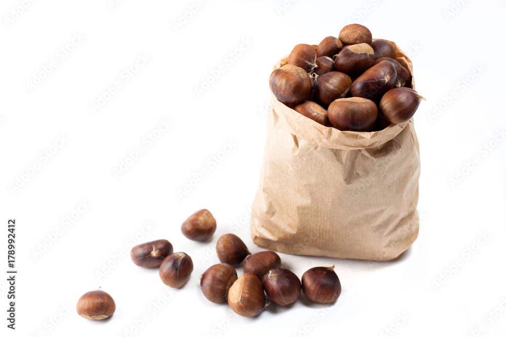 edible chestnuts - a bag of fresh, raw chestnuts sprinkled on a white background
