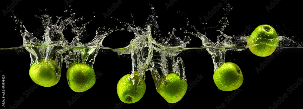 Naklejka Zielony jabłko spada w wodzie na czarnym tle