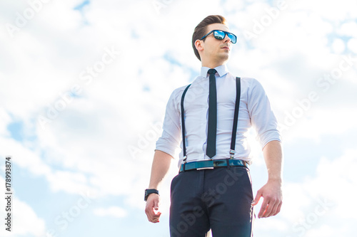 Serious young busunessman in white shirt, tie, braces and sunglasses stand on the roof © Ivan Traimak