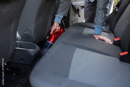 Auto service staff cleaning car with portable vacuum