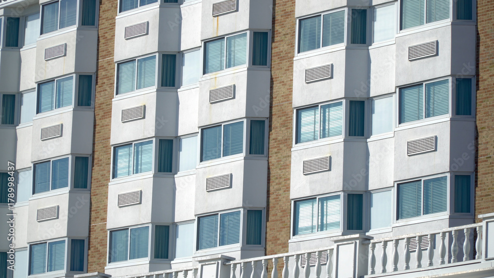 Establishing shot day time exterior close up hotel room window facade. Generic architecture design of bay windows and air conditioning units of five star vacation resort location