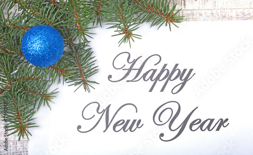 Text happy new year on paper with fur-tree  branches  colored glass balls   decoration and cones on a wooden background