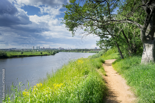 Walking path along the Moscow river. Blue sky and green grass