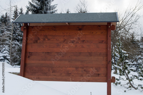 Empty wooden sign in winter landscape and surrounded by snow