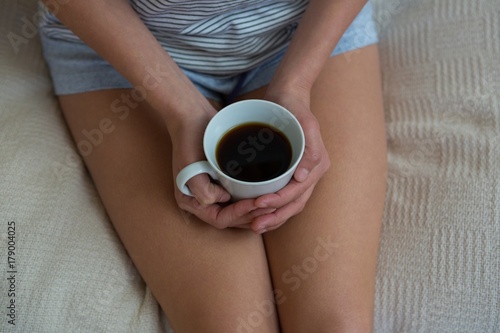 Mid section of woman having black coffee