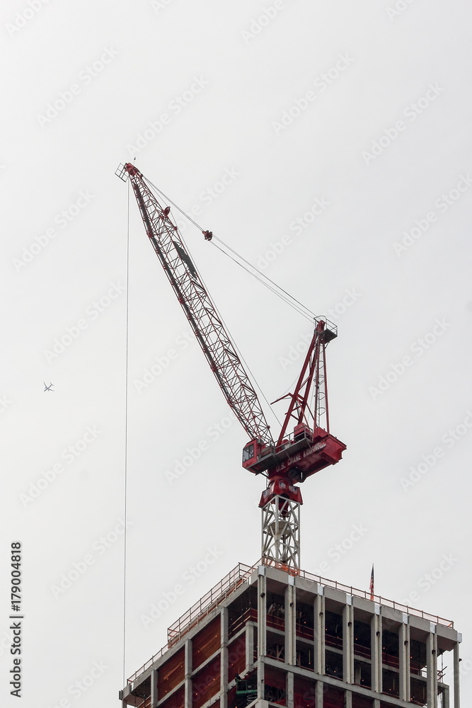 A crane sits on top of a building being constructed in central manhattan. A crane sits on top of a building being constructed in central manhattan.