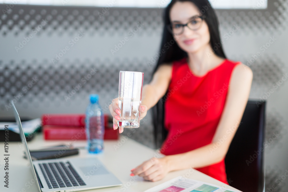 Pretty, young businesslady in red dress and glasses sit at the table and work Pretty, young businesslady in red dress and glasses sit at the table and work