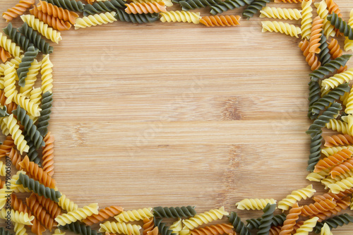 Different types of Italian pasta making a frame on rustic wooden table