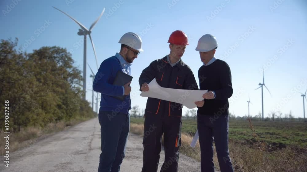 Team of three competitive coworkers collaborating on plan of building new sources of energy in field. Team of three competitive coworkers collaborating on plan of building new sources of energy in field.