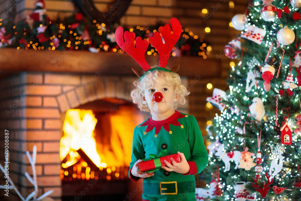 Child at Christmas tree and fireplace on Xmas eve Child at Christmas tree and fireplace on Xmas eve