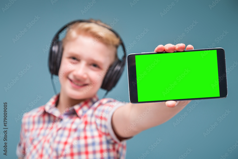 Teenager with headphones shows smartphone display Teenager with headphones shows smartphone display