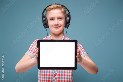 Teenager with headphones shows tablet display, photo with space for text photo