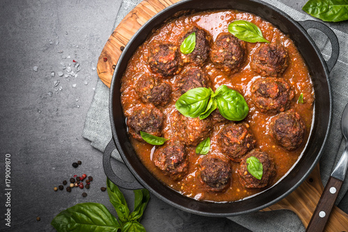 Meatballs in tomato sauce on a black background.