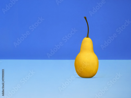 Pear Pop art One yellow pear is standing upright on blue background Trendy still life with fruit