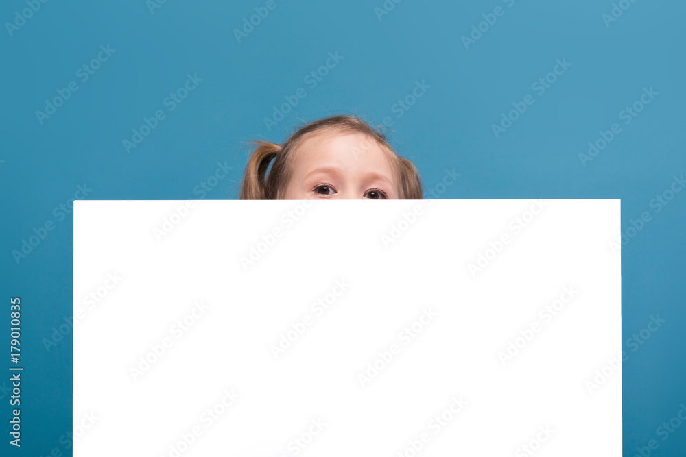 Attractive little cute girl in pink shirt with monkey and blue trousers hold empty poster Attractive little cute girl in pink shirt with monkey and blue trousers hold empty poster