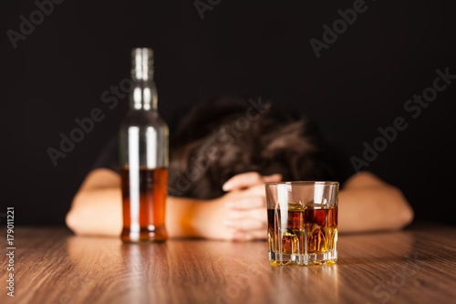 Drunk Woman Sleeping At Bar Counter with a Bottle and a Glass of