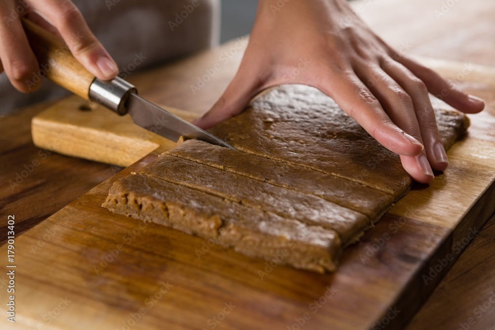 Woman slicing dough on chopping board