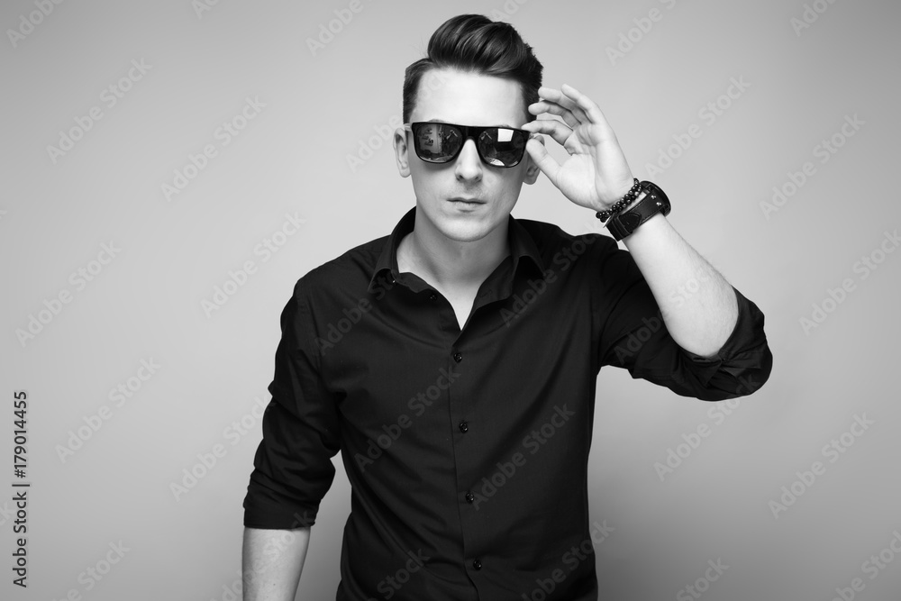 Handsome young businessman in costly watch, sunglasses and black shirt Handsome young businessman in costly watch, sunglasses and black shirt