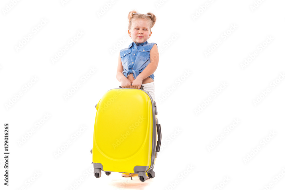 Attructive cute little girl in blue shirt, white shorts and sunglasses stand near yellow suitcase Attructive cute little girl in blue shirt, white shorts and sunglasses stand near yellow suitcase
