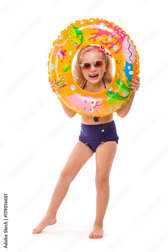 Pretty little girl in red striped bikini, blue bottoms, sunglasses and pink wreath stand stand with rubber ring in hand Pretty little girl in red striped bikini, blue bottoms, sunglasses and pink wreath stand stand with rubber ring in hand