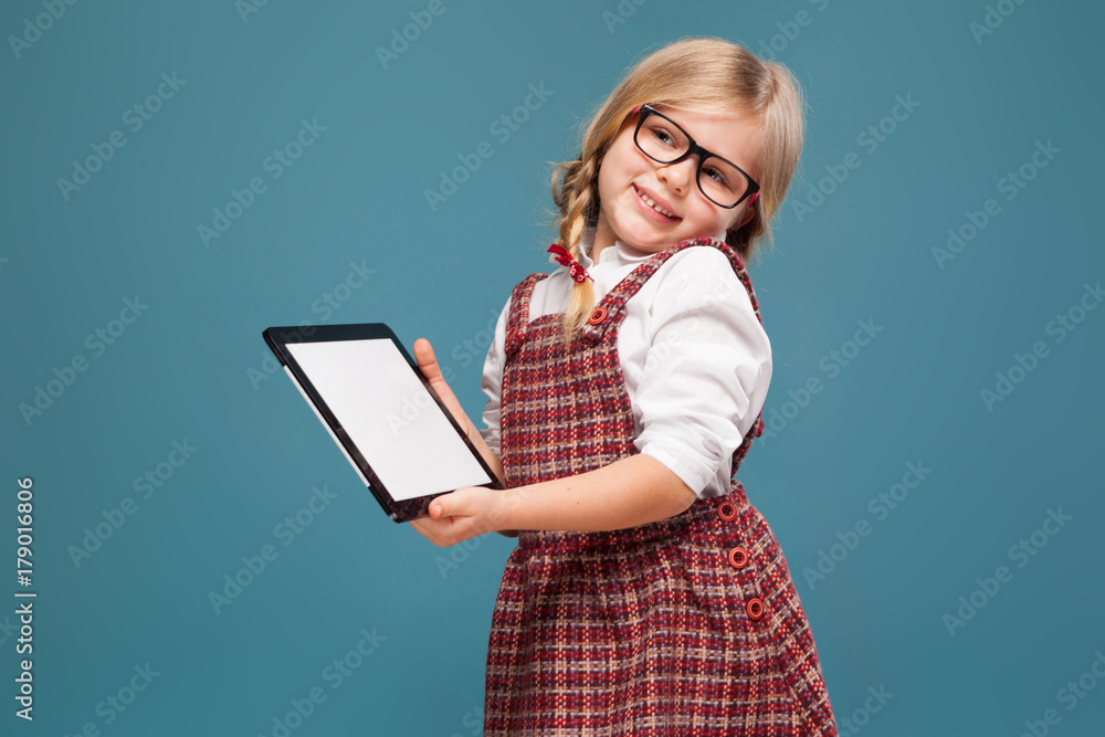 Cute little girl in red dress, white shirt and glasses holds empty tablet Cute little girl in red dress, white shirt and glasses holds empty tablet